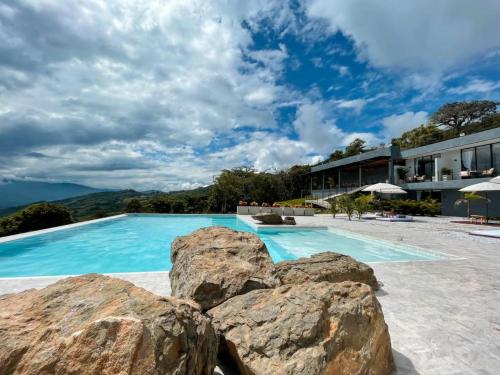 a large swimming pool with rocks in front of a building at Santuario Luxury Eco Hotel in Villeta