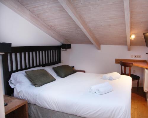 a bedroom with a white bed with two towels on it at Hotel Cuéntame La Puebla in Burgos