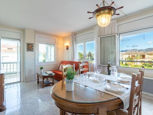 a dining room with a table and chairs and windows at Apartment Sol i Canal by Interhome in Empuriabrava