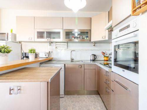 una cocina con armarios blancos y electrodomésticos de acero inoxidable en Apartment Sol i Canal by Interhome, en Empuriabrava