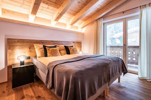 um quarto com uma cama grande e uma janela grande em Chalet Alpendomizil Ahorn em Mayrhofen