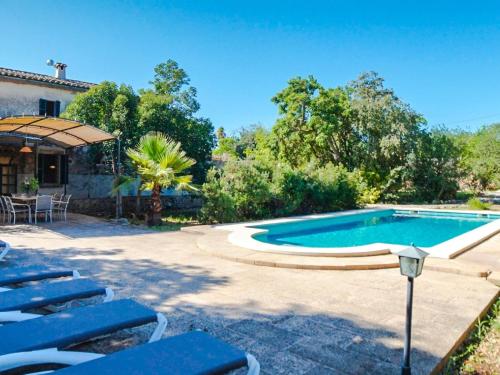 a swimming pool in a yard with blue chairs at Holiday Home Cas Frare ESB100 by Interhome in Establiments