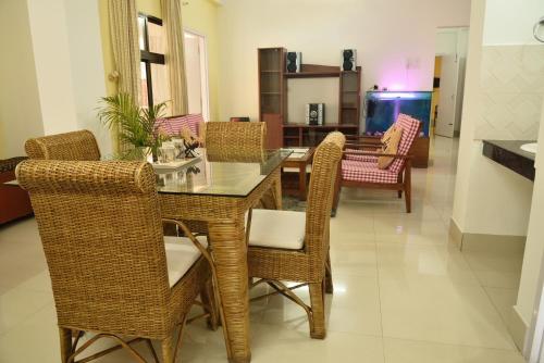a dining room with a glass table and wicker chairs at GRUHAM SOJOURN HOMESTAY in Guwahati