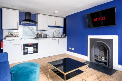 uma sala de estar com uma parede azul e uma lareira em Darcys' Pride em Bath