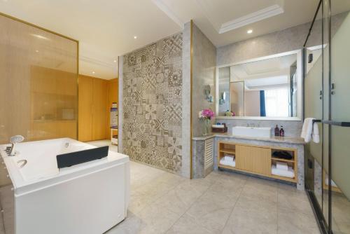 La salle de bains est pourvue d'une baignoire, d'un lavabo et d'une douche. dans l'établissement OBOR Hotel, à Ürümqi