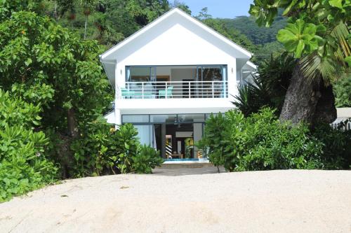 una casa blanca en la playa con un árbol en Lyla Beach Villa, en Pointe Au Sel 