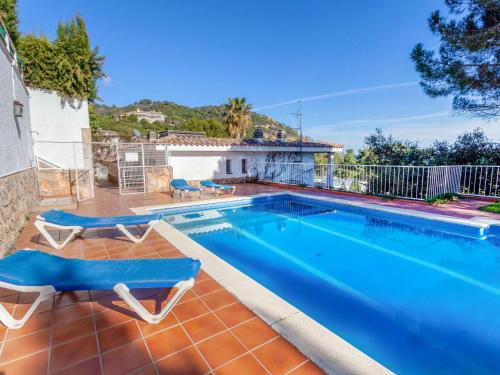 a swimming pool with two lounge chairs next to a house at Holiday Home Berganti by Interhome in Tossa de Mar