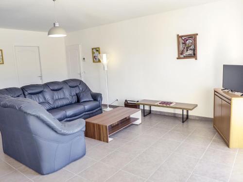 uma sala de estar com um sofá azul e uma mesa em Holiday Home Philibert by Interhome em Carcans