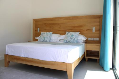 a bedroom with a large bed with a wooden headboard at Lyla Beach Villa in Pointe Au Sel 