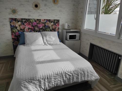 een slaapkamer met een groot bed met een bloemrijk hoofdeinde bij Chambre HORTENSIA in Questembert