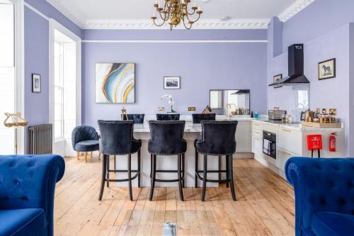 a kitchen with blue walls and a bar with stools at Darcys' View in Bath