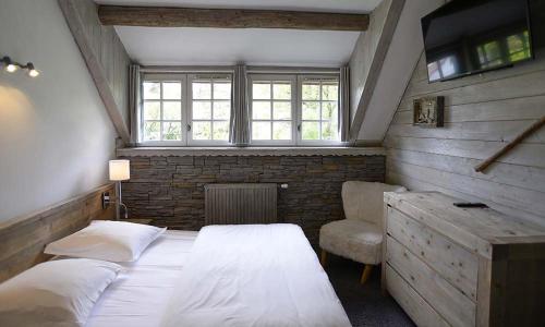 a bedroom with a bed and a desk and a window at Le Moulin de Lily in Palaiseau