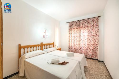 a bedroom with a white bed with a window at Apartamentos Vista Alegre Casa Azahar in Alcossebre