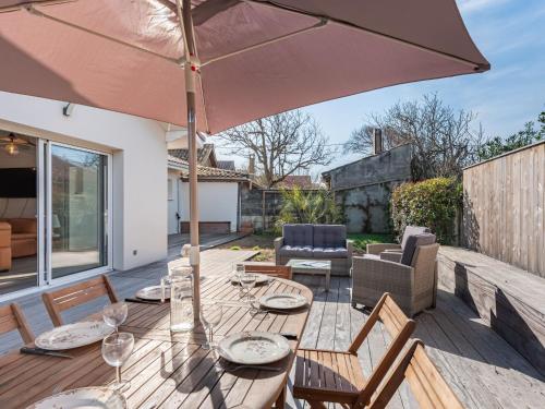eine Terrasse mit einem Holztisch und einem Sonnenschirm in der Unterkunft Holiday Home Villa Horizon by Interhome in Lacanau-Océan