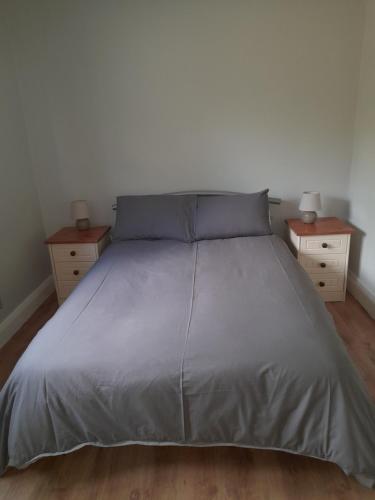 Una cama con una manta gris y dos mesitas de noche en The Villa en Lettermacaward