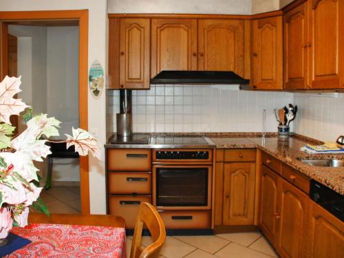 a kitchen with wooden cabinets and a stove top oven at Holiday Home Pina by Interhome in Malvaglia