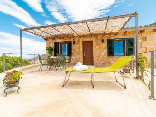 eine Terrasse eines Hauses mit einem gelben Tisch und Stühlen in der Unterkunft Holiday Home Sa Caseta des Camp by Interhome in Banyalbufar