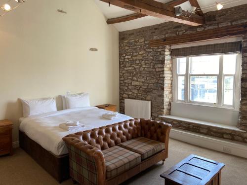 een slaapkamer met een bed, een bank en een raam bij The Greyhound Hotel in Shap