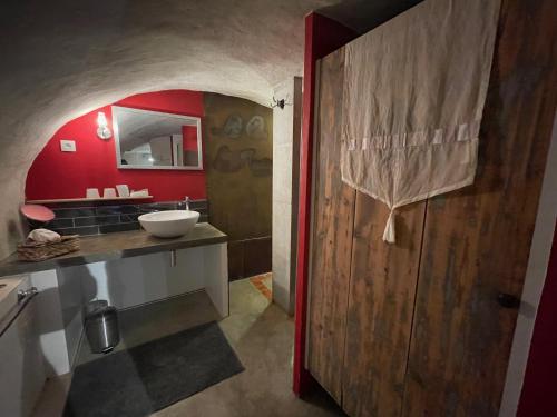 a bathroom with a sink and a red wall at La Maison de Sofia in Vallabrix