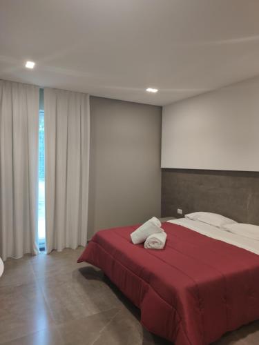 a bedroom with a large bed with a red blanket at Hotel Valle Verde in Grammichele