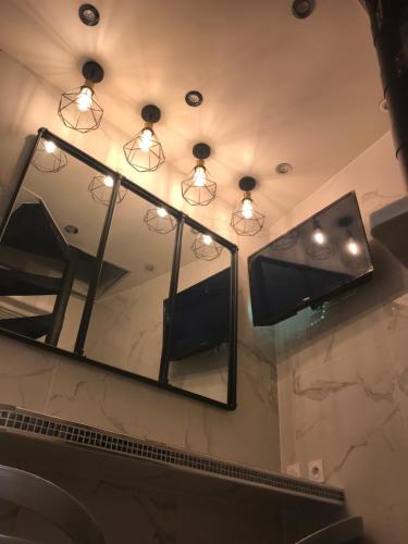 La salle de bains est pourvue d'un miroir et de lumières murales. dans l'établissement Superbe Triplex au Coeur de Montorgueil, à Paris