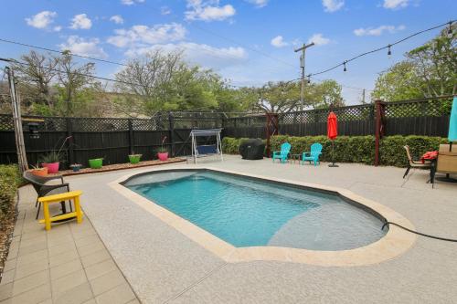 a swimming pool in a yard with chairs and a fence at AbFab Seaside Cottage in Galveston