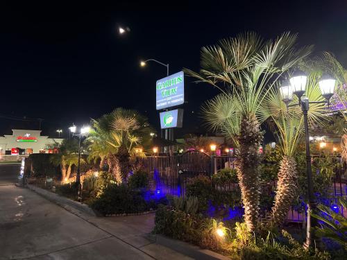 a sign for a hotel with palm trees at night at Garden View Inn in Fresno