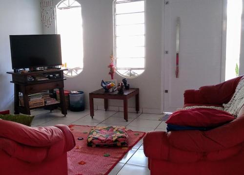 uma sala de estar com 2 cadeiras vermelhas e uma televisão de ecrã plano em Casa Amarela em Uberlândia