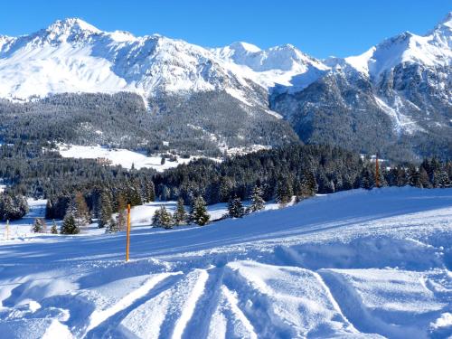 a snow covered slope with mountains in the background at Zuhause in den Alpen Ihre Ferienwohnung mit Hallenbad und Sauna in Lenzerheide