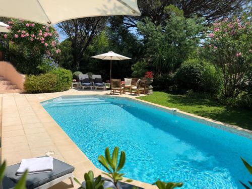 a swimming pool with an umbrella and some chairs at Villa Golf Azur in Saint-Raphaël