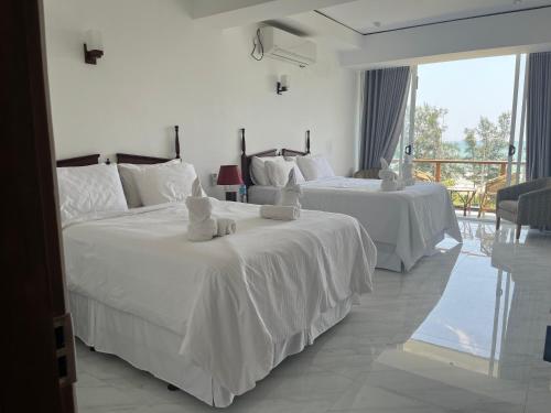 two beds in a hotel room with white sheets at Bayfront in Weligama