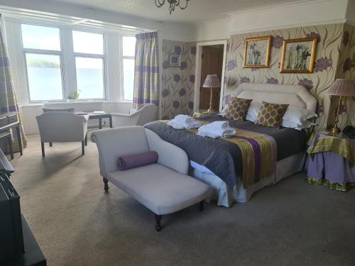 a bedroom with a king sized bed and a chair at Balcary Bay Country House Hotel in Auchencairn