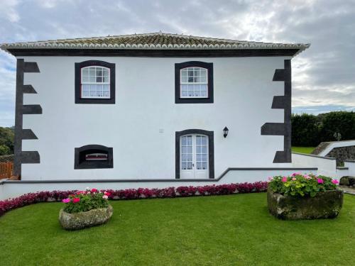 ein weißes Haus mit Blumen im Hof in der Unterkunft Casa do Avô José Alves in Praia da Vitória