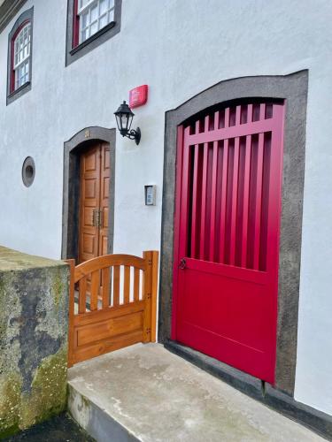 two red garage doors on a white building at Casa do Avô José Alves in Praia da Vitória