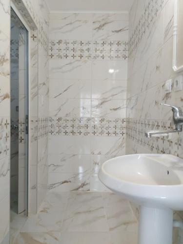 a white bathroom with a sink and a shower at Guest House Perla in Obzor