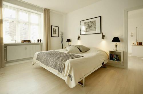 a white bedroom with a large bed and a window at ApartmentInCopenhagen Apartment 1167 in Copenhagen