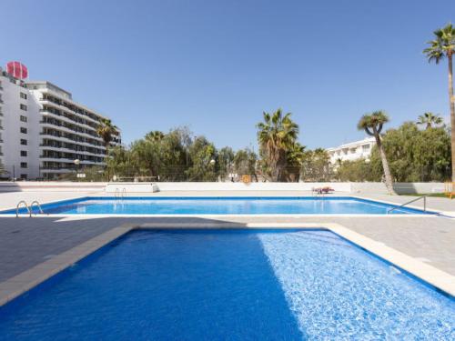 a large swimming pool with blue water in front of a building at Duplex Las Americas in Playa de las Americas