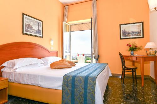a bedroom with a bed and a desk and a window at Hotel Villa Fernanda in Massa Lubrense