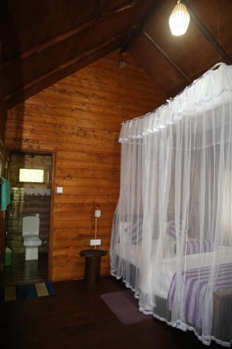 1 dormitorio con 1 cama con cortina blanca en Jungle Face Inn, en Ella