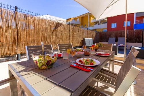 - une table en bois avec des bols de nourriture sur la terrasse dans l'établissement SELECT'SO HOME - Résidence Le Poséidon - Mazet en Duplex - Prestations de qualité & Services Hôteliers - POS-D, à Bormes-les-Mimosas