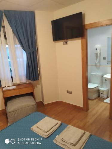 a room with a bathroom with a toilet and a tv at Hotel Sol de la Blanca in Cudillero