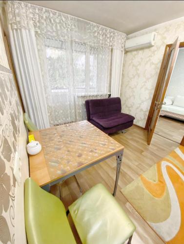 sala de estar con mesa y silla púrpura en Apartments Ahmetova 4 21 en Almaty