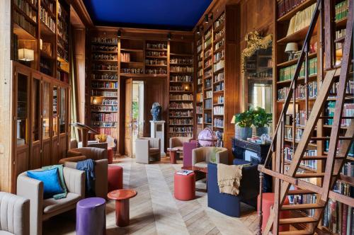 uma biblioteca com cadeiras e estantes em Maison du Val - Les Maisons de Campagne em Saint-Germain-en-Laye