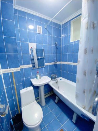 La salle de bains est pourvue de carrelage bleu, de toilettes et d'un lavabo. dans l'établissement Ахметова 6 7, à Almaty