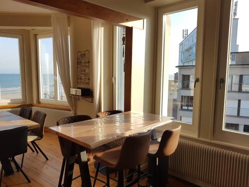 una mesa y sillas en una habitación con ventanas en Apt 6 pers. Duplex vue mer avec charme de l'ancien, en Bray-Dunes