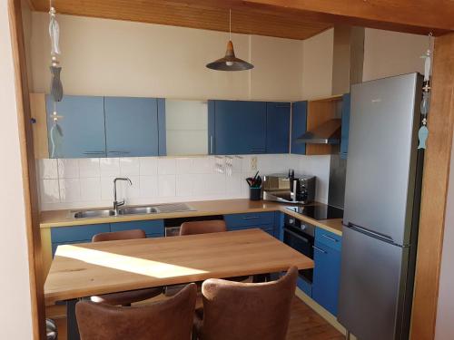 a kitchen with a wooden table and blue cabinets at Apt 6 pers. Duplex vue mer avec charme de l'ancien in Bray-Dunes