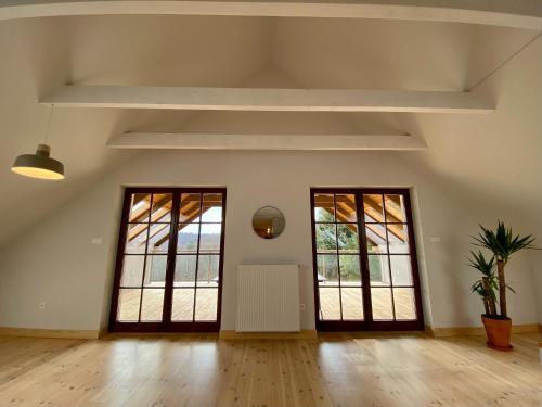 an empty room with two large windows and wooden floors at Sztukówka Winery in Frysztak