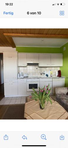 a kitchen with white cabinets and a vase of flowers on a table at Pension Erna in Zwiesel