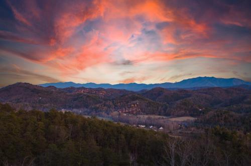 a sunset over a mountain range with a city at Heavenly Vista at Crown Point cabin in Sevierville