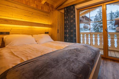 Cama en habitación de madera con ventana grande en Falkensteinalm Hochkrimml en Krimml